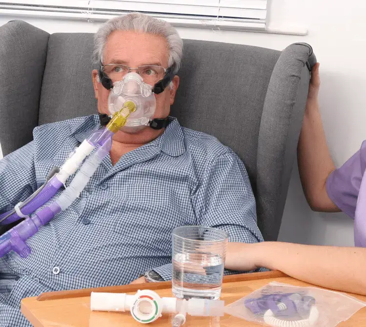 A man sitting in a chair with a breathing mask, showing CPAP breathing circuits by Armstrong Medical A man sitting in a chair with a breathing mask, showing CPAP breathing circuits by Armstrong Medical